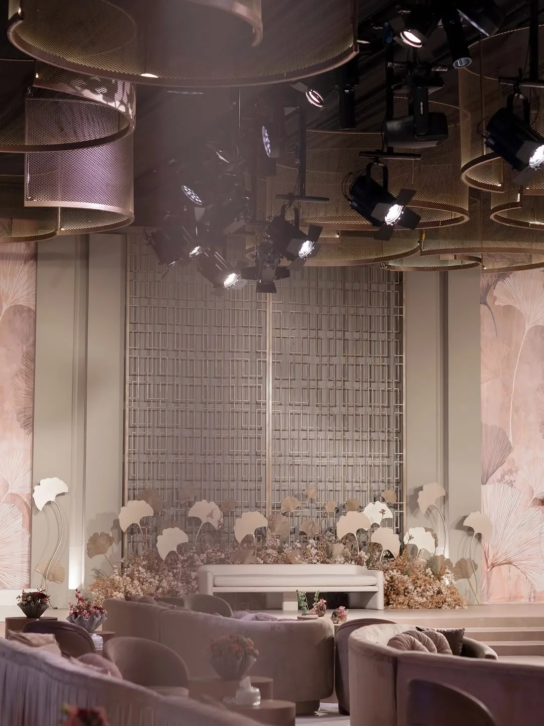 Wedding hall with a sculpted ginkgo-leaf stage, lilac velvet lounges and stage lighting overhead