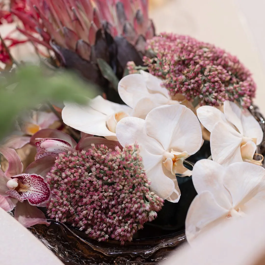 White orchids with pink seasonal flowers in a low arrangement