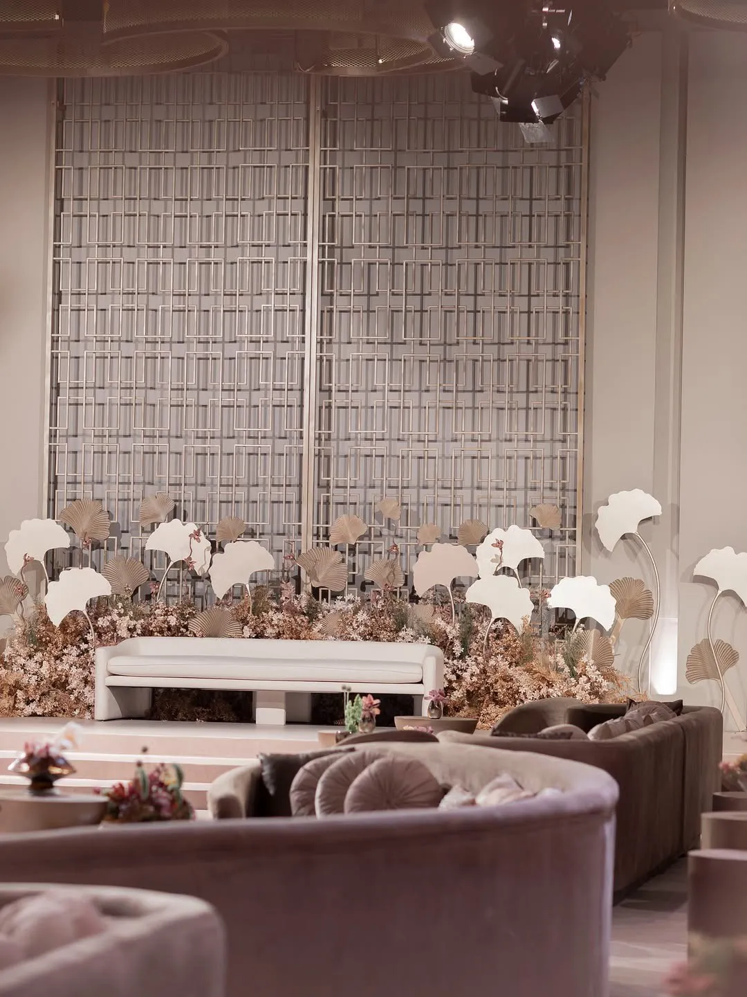 Bridal stage with a white sofa, ginkgo-leaf sculptures and layered dried florals