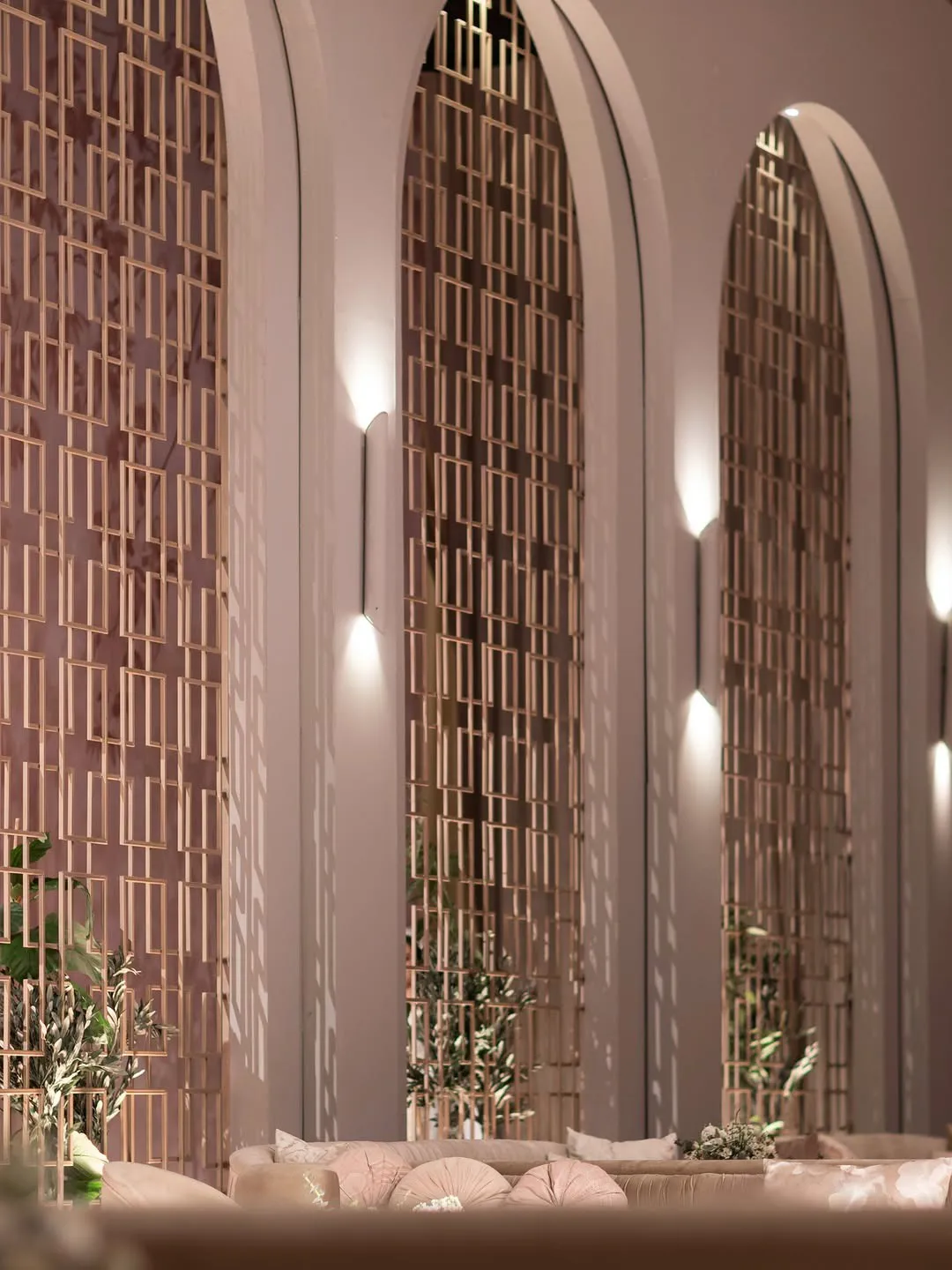 Arched lattice screens and slim wall lights beside lounge seating